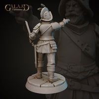 Rear three-quarter view of the same unpainted grey resin Conquistador miniature by Galaad Miniatures, showing the back detail of his layered armour, shoulder plate, cross-body strap, and feathered morion helmet. The short sword is visible in his lowered right hand and his left arm is outstretched. The cobblestone base detail is clearly visible.