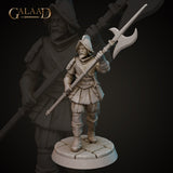 Front view of an unpainted grey resin 3D printed miniature of a stocky bearded soldier in padded armour and a wide-brimmed morion helmet, striding forward while raising a long halberd. Sculpted by Galaad Miniatures at 32mm scale on a cobblestone base.
