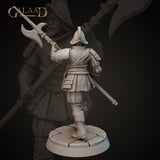 Rear view of the same unpainted grey resin conquistador miniature, showing detailed back armour plating, a belted sash, greaves, and the halberd raised overhead. Sculpted by Galaad Miniatures at 32mm scale on a cobblestone base.