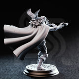 Photograph of unpainted grey resin Crow Eyes Blind Gunslinger miniature — rear three-quarter view showing long hair beneath the blindfold wrap, the textured woven lining of the billowing cape, crow familiar visible from behind with wings spread, and the cobblestone round base