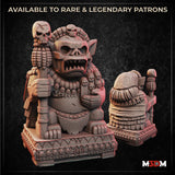 Digital render of the Cursed Fertility Idol miniature showing front and rear views — a squat demonic figure with a wide snarling mouth, pointed ears, and a necklace of tiny soul-faces, clutching a skull-topped staff, seated on an ornately carved plinth covered in miniature anguished faces