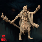 Three-quarter rear view render of the Deathlock Mastermind miniature showing the sweeping cape, layered robes with jagged hem, horned skull crown, and bone staff extended outward — unpainted gold-toned render by Monster Atlas