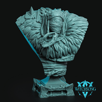 A large-scale bust of a mummified creature with a single lidless eye, wrapped in ancient linen bandages, encircled by a wide collar of layered feathers. One gnarled limb reaches forward through the plumage. A sigil-etched crown sits atop the wrapped head. The bust rests on a detailed stone plinth with chiselled stonework. Sculpt by Witchsong Miniatures.