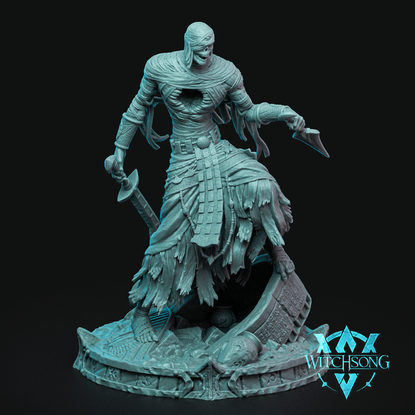 Unpainted grey resin miniature of the Desiccated Tyrant by Witchsong Miniatures — a bandaged mummy lord striding forward over ruined carved stonework, wielding a hand axe in the left hand and a curved blade in the right, with ragged linen wrappings, exposed ribcage, and a skull-like snarling face. Scenic base features runes and tomb rubble.