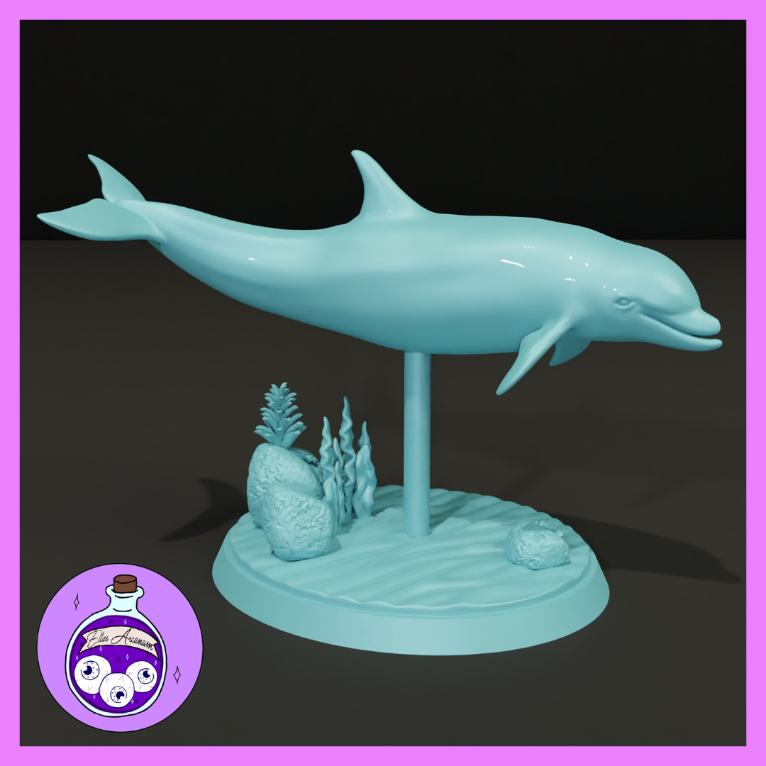 A dolphin miniature gliding horizontally atop a raised pole mount, set on a round scenic base of rippled sand, rounded rocks, and sculpted kelp. Sculpt by Ella's Arcanum Minis.