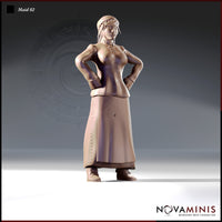 32mm scale unpainted resin miniature of Maid 02 by Novaminis — a medieval woman in a fitted bodice and long laced skirt, standing with both hands planted firmly on her hips in a confident, authoritative pose