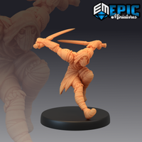Unpainted resin miniature of a dual-wielding elf rogue in a dynamic leaping pose, wrapped in linen bandages with twin short swords raised, hooded face, on a round black base — 32mm scale by Epic Miniatures