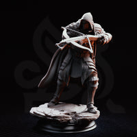 Crossbow knight in a low crouch behind a large riveted wooden pavise shield, crossbow levelled, chainmail hood drawn low over a masked face. Stone rubble base. Sculpt by DM Stash.