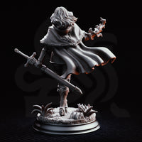 Erina of Amarth striding forward with a longsword lowered at her side and her right hand raised, channelling arcane energy. She wears a layered longcoat, travelling armour, and a circular medallion. Sculpt by DM Stash.