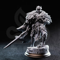 Photograph of unpainted grey resin Eulysses the Eversighted miniature — front-facing view showing layered feather pauldrons, sun-disc chest medallions, feather tassels at the waist, and articulated leg armour on a cobblestone base