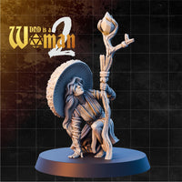 Firbolg druid kneeling with a large mushroom cap fanning behind her, gripping a rope-and-feather-bound nature staff topped with a closed bud. Sculpt by DnD is a Woman.