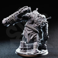 Rear view of the unpainted grey resin Ettin Brute miniature Flim and Krim, showing the broad matted back, ragged tattered cloth, the overhead club swing from behind, and the detailed rubble base with broken column fragments