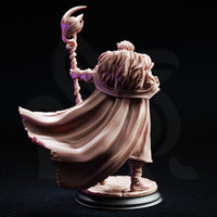Frederik Vahlen Professor of Progress 32mm resin miniature by DM Stash — rear view showing unpainted grey resin sculpt with dramatic billowing cloak in deep sweeping folds, wild layered hair visible above the fur mantle, and the crescent-topped twisted staff raised in the outstretched hand