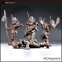 Three goblin warrior miniatures grouped together: a spear-bearer standing upright in spiked armour, a wide-eyed berserker with arms outstretched and a short sword, and a fallen goblin face-down on the ground. Sculpts by Novaminis.