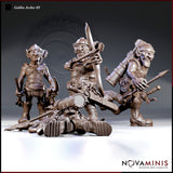 Three goblin archer sculpts by Novaminis displayed together: a standing goblin with blades and back quiver, a seated goblin drawing a longbow in heavy chain armour, and a striding goblin gripping a mace, with a fallen goblin and large mechanical weapon piece in the foreground.