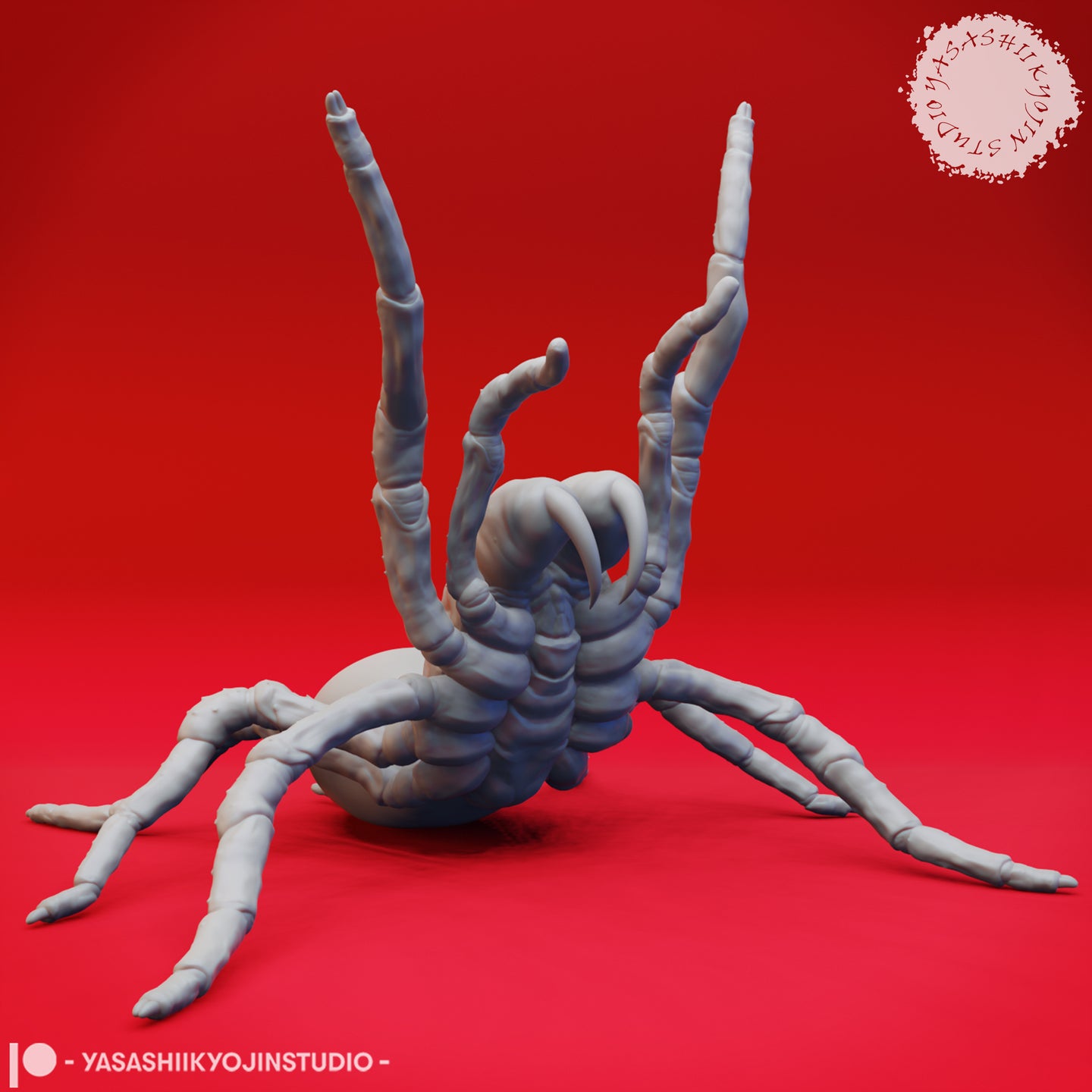Grey unpainted resin giant spider miniature in a rearing threat pose — forelegs raised high, curved fangs spread wide, viewed from the front at low angle against a red background. Sculpted by Yasashii Kyojin Studio.