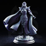 Glynaria drow priestess miniature facing forward, armoured in angular elven plate with leaf motifs, long robes billowing wide to her left, one hand raised with fingers extended, on a sculpted swirling stone base. DM Stash.