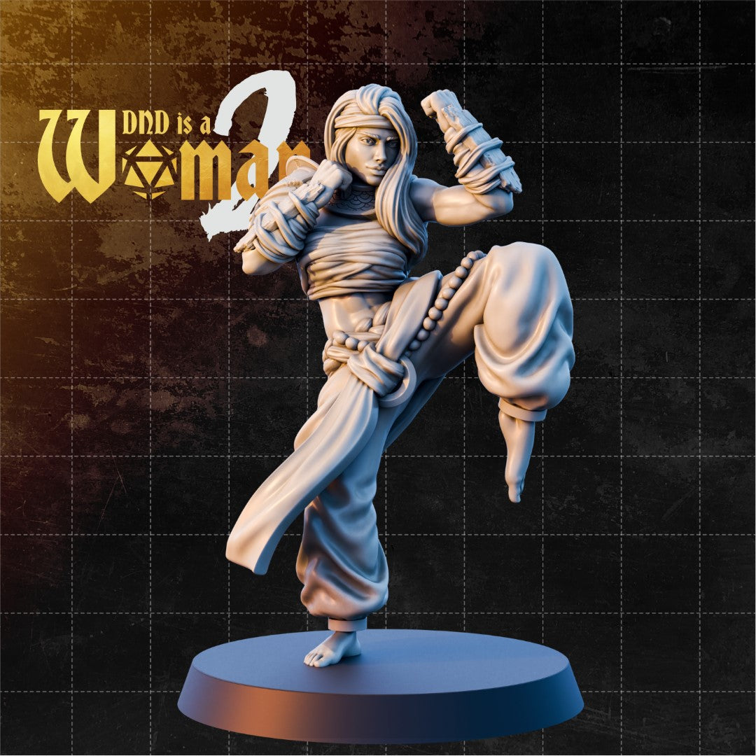 Goliath Monk Axya sculpt by DnD Is A Woman — female figure mid-high kick, knee raised, both arms coiled with cloth wrappings, loose flowing hair, prayer-bead belt, bare feet.