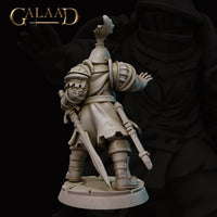Rear view of the same unpainted grey resin Queen's Guard 03 miniature showing a gear satchel secured to the back, segmented pauldrons, a trailing long sword, and a fabric tabard over plate armour, with the cracked stone base visible beneath