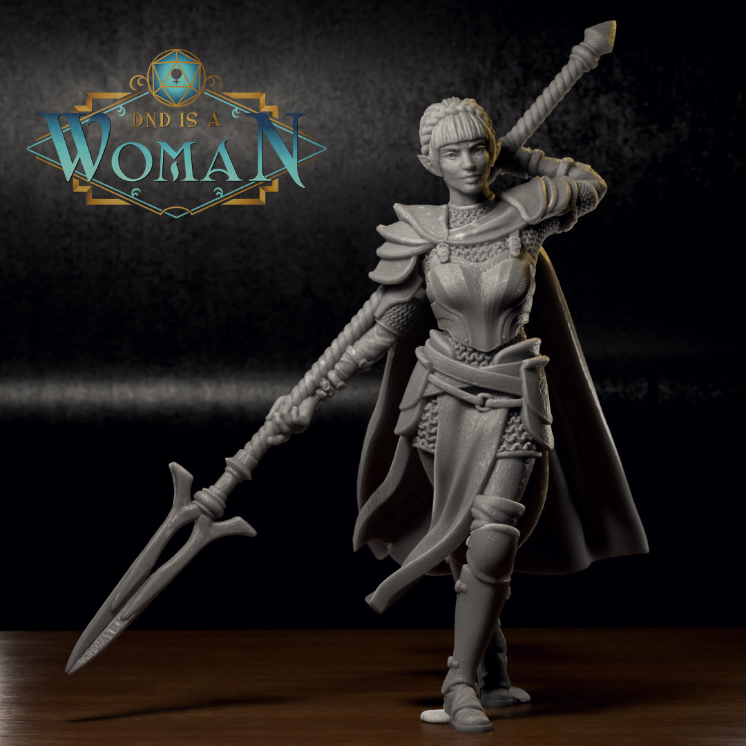 Photograph of a printed and unpainted grey resin Savine half-elf fighter miniature on a dark surface. The 32mm scale mini shows the same dynamic sword-raised pose with cape, layered armour, and braided hair. The level of detail in the chainmail, buckles, and sword grip is clearly visible in the physical print.