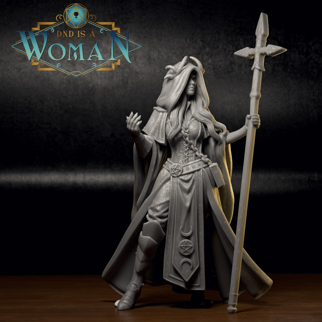 Grey resin hexblood cleric with small curved horns beneath a large hood, long flowing hair, wide-sleeved robes with crescent moon and pentagram embossing, raising one hand with spread fingers while holding a cross-tipped staff. Sculpt by DnD Is A Woman.