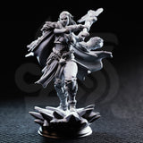 Unpainted grey resin miniature of Ice Heart by DM Stash — front view showing dynamic mid-stride pose, fur pauldrons, layered leather armour, and frost magic effect on outstretched weapon arm, on a splintered ice crystal base