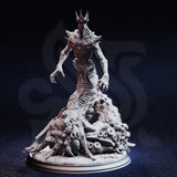 Front view of the unpainted grey resin Idinhelieth miniature on a round display base, showing the full skeletal torso, bone-spur crown, outstretched clawed arms, and detailed scenic base packed with writhing bodies and buboes