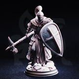 Front view of an unpainted grey resin Jeremus of Jochenia miniature — a heavily armoured crusader knight with layered plate and scale-backed robes, plumed visor helm, ornate war-hammer extended forward, and a battle-scarred kite shield raised at his side, mounted on a rubble scenic base