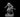 Grey resin digital render of a crouching kobold warrior miniature at 32mm scale, armed with a short blade held in both hands, featuring a horned reptilian head with open jaws, heavily scaled body, and clawed hands and feet, mounted on a plain round base