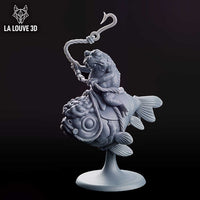 A warty toad gripping a fishing rod seated atop a large, round-bodied fish tied with rope. The rod curves upward to a barbed hook. Decorative base. La Louve 3D.