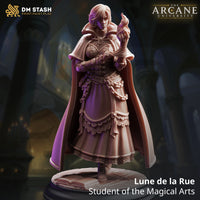 Lune de la Rue Student of the Magical Arts 32mm resin miniature by DM Stash — digital render showing a young female mage in a flowing academic cloak and layered skirt, raising a small flame of arcane fire in her right hand, with keys and a chain at her belt and a tome-inscribed flagstone base