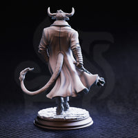 Rear-view photograph of the Marchese di Houf unpainted grey resin miniature. The back of the long overcoat is richly detailed with stitched seams and flowing fabric. The tail sweeps out from beneath the coat hem. The ribbed detailing on the sleeves and the textured cobblestone base are clearly visible from this angle.