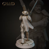 Rear view of the same unpainted grey resin mercenary miniature showing a sweeping travelling cloak, back detail of the armoured pauldrons and leather skirt, feathered hat brim, and longsword raised in the right hand, on a cobblestone base — sculpted by Galaad Miniatures