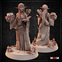 Moon Elf Librarian Cleric by Mia Kay M3DM — standing figure holding an open book, with a scroll in one hand and a stack of tomes cradled at her side, wearing ornately detailed robes with floral scrollwork, long straight hair and a delicate tiara, base scattered with candles and crystal formations.