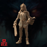 Unpainted sandy resin miniature of Nat in an alternative pose, facing forward with a flowing cloak billowing behind her. She holds a shorter wooden weapon at her side and has her other hand loosely balled. Her long hair is looser and slightly more tousled in this sculpt. The belted tunic and ankle boots remain consistent with the other poses. Monster Atlas branding visible in the lower left corner.