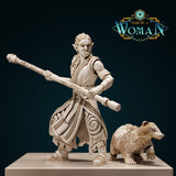 Digital render of Xira the Orc Monk miniature — unpainted cream resin, holding a long diagonal bone staff in a wide combat stance, wearing Celtic knotwork robes with a sash and bracers, with a detailed shaggy bear companion beside her. Front view.