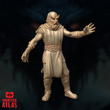 Front-facing render of the Otiluke archmage miniature showing a bald bearded male figure in long robes with a studded belt, one arm extended wide to the side and the other hanging open — unpainted tan resin render by Monster Atlas at 32mm scale