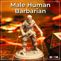 Photograph of a printed unpainted grey resin male human barbarian miniature on a tabletop gaming mat beside a large gold and red d20 die, showing the full sculpt with cloth-wrapped body, bone club, and detailed scenic desert base