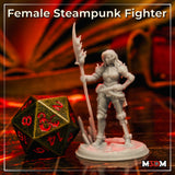 Photograph of the printed Female Steampunk Fighter miniature in unpainted grey resin, posed with hand on hip and a flame-tipped spear, wearing detailed steampunk plate armour with a layered skirt and mechanical leg guards, on a textured base, shown alongside a large gold and red D20 for scale.