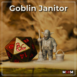 Photograph of a printed and unpainted grey resin goblin janitor miniature at 32mm scale, posed beside a D20 dice for scale reference — goblin holds a mop and stands next to a wooden bucket, expression stern and grumpy