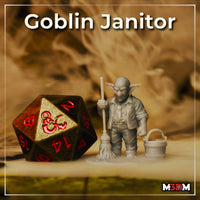 Photograph of a printed and unpainted grey resin goblin janitor miniature at 32mm scale, posed beside a D20 dice for scale reference — goblin holds a mop and stands next to a wooden bucket, expression stern and grumpy