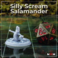 Unpainted grey resin Silly Scream Salamander miniature photographed on a gaming mat next to a large D20 dice for scale — the salamander is seated on a lily pad base, mouth open wide in a dramatic scream, arms outstretched