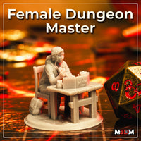 Photograph of a printed unpainted grey resin miniature of a female Dungeon Master seated at a wooden table with a GM screen and tankard, shown at an angle on a gaming mat alongside a large d20 die for scale reference.