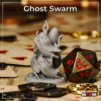 Unpainted grey resin Ghost Swarm miniature photographed on a tabletop surrounded by playing cards, gold coins, and a large metal D20, showing the swarm of tangled ghost figures at 32mm scale
