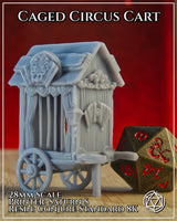 Photograph of the printed Caged Circus Cart terrain piece in unpainted grey resin, shown at 28mm scale alongside a large bronze D20 die for size reference, displaying the carved decorative facade, curtained cage bars, and wheeled base with draw-shaft