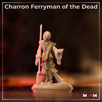 Same hooded ferryman sculpt shown from a slightly raised angle under warm studio lighting, revealing the hollow mask-like face beneath the deep cowl, ornate coin-decorated collar, and heavy draped robes tapering to a rocky base. Sculpt by Mia Kay M3DM.