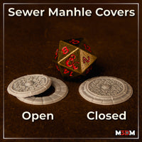 Unpainted resin sewer manhole cover scatter piece, shown in two states: lid displaced to reveal open hole, and lid seated flat. Bold geometric relief channels cover the disc surface, with a crenellated cobblestone outer ring. Sculpt by Mia Kay M3DM.