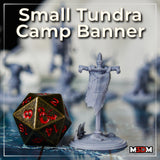 Painted grey prototype of the full ram-skull tundra banner standing next to a large bronze D20 die, showing scale; horned skull at top, bones at crossbeam ends, antler base visible. Sculpt by Mia Kay M3DM.