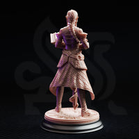 Unpainted resin miniature of Proctor Synthelia by DM Stash — rear view revealing a long detailed braid, full geometric quilting across the coat, belted armour, and the engraved runic base, demonstrating the sculpt's back detail on a black display stand