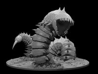 Massive segmented worm creature rearing upward with jaws wide open, rows of inward-curving fangs visible. Thick spined chitin plating covers the body, dorsal spikes crown the head, and two barbed foreclaws extend forward. Mounted on a rubble-strewn base suggesting ground eruption. Sculpt by MZ4250.